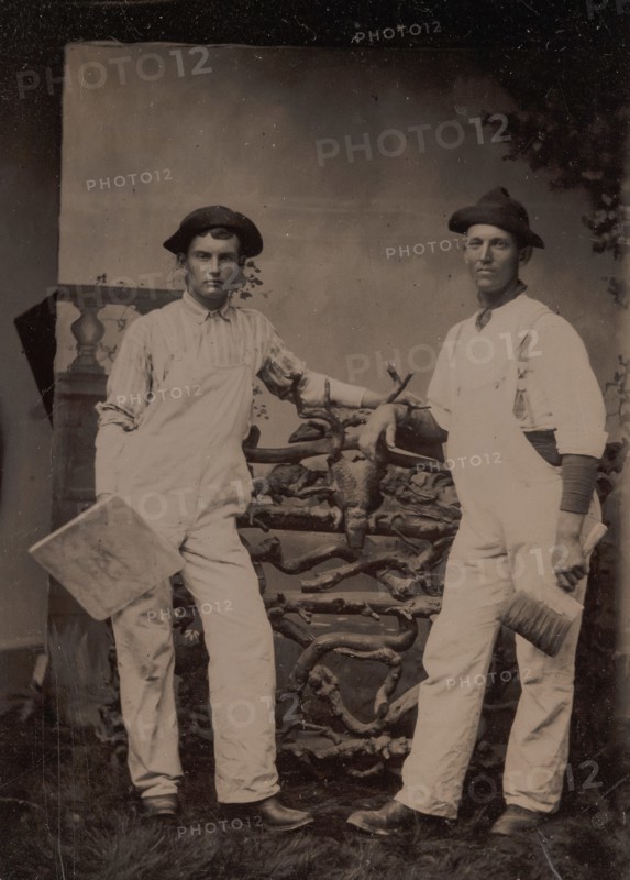 Two Plasterers in Overalls Leaning on a Rustic Fence, 1870s-80s.