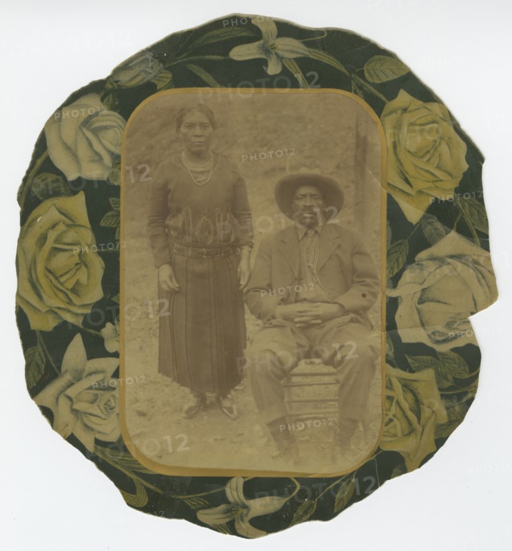 Photographic portrait of a man and woman on floral paper backing, early 20th century. Creator: Unknown.