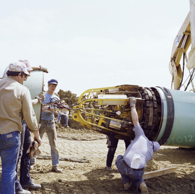 A team of men joining two steel pipes together on the Martin pipeline, Hertfordshire, 07/07/1981. Creator: John Laing plc.