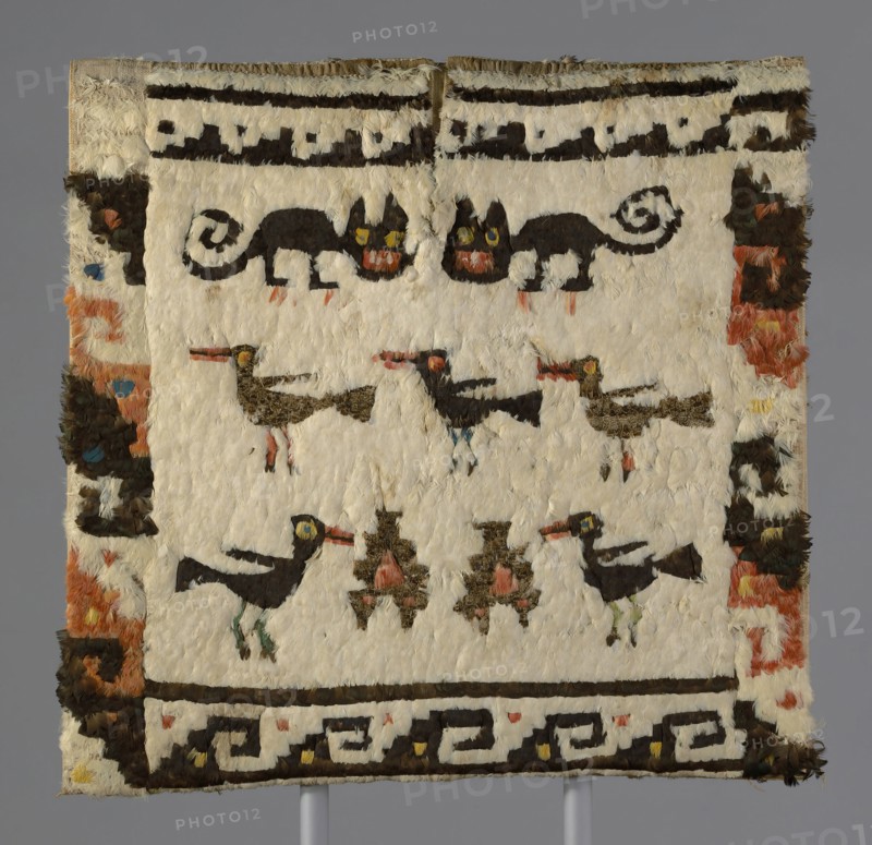 Feathered Tunic, Peru, 1470/1532. Cat and bird motif embellished with rare and valuable feathers from macaws, parrots, toucans, cotingas and tanagers from the tropical forests of South America, transported across the treacherous peaks of the Andes. The tunic was buried with its owner in dark, dry tomb which preserved its bright colours.