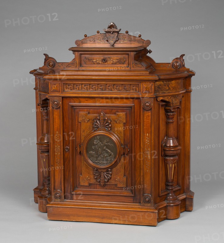 Cabinet, 1875/77. Greek key pattern, turned and carved wood, bronze plaque depicting shepherd, shepherdess and sheep.