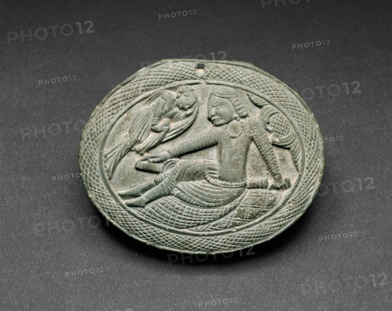 Oval Cosmetic Box Lid with a Man Being Entertained by a Lyrist, 5th/6th century. Ancient region of Gandhara (modern Pakistan).
