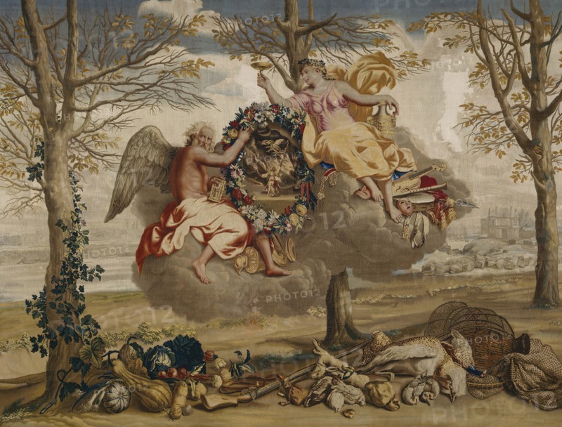 Winter, from The Seasons, Paris, 1700/20. Saturn (god of agriculture and time) and Juventas (cupbearer to the gods on Mount Olympus) floating on a cloud. Below are winter vegetables, a gun, nets and game from a hunt. In the background is the Palais du Louvre in Paris. Woven at the workshop of Etienne Le Blond and Jean de La Croix at the Manufacture Royale des Gobelins, after a design by Charles Le Brun. Detail from a larger artwork.