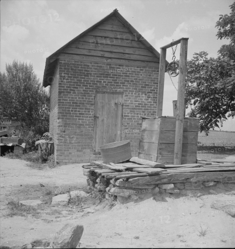 Well and old plantation smokehouse, Chesnee, South Carolina, 1937. Creator: Dorothea Lange.