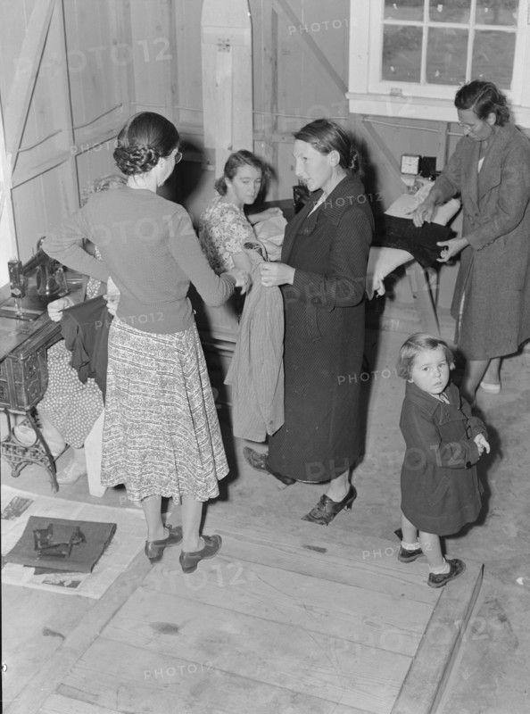 Camper receives help in fitting a coat from WPA sewing instructor, FSA, California, 1938. Creator: Dorothea Lange.