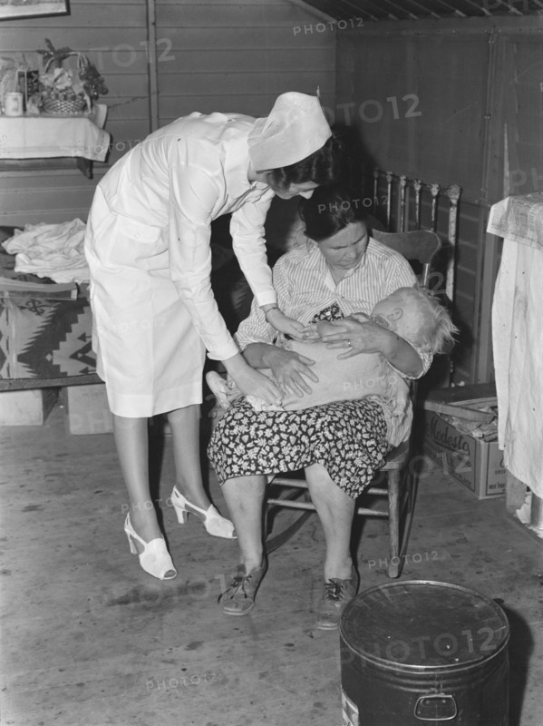 Nurse attending sick baby, FSA camp, Farmersville, Tulare County, California, 1939. Creator: Dorothea Lange.