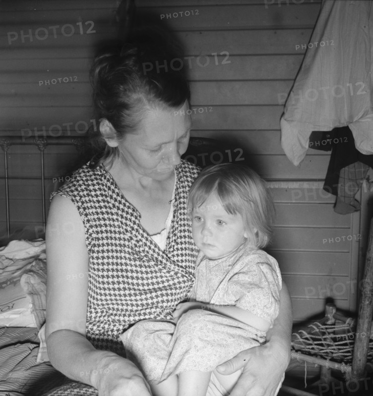 Mother from Oklahoma, awaits visit of resident nurse for sick baby, FSA camp, Farmersville, CA, 1939 Creator: Dorothea Lange.