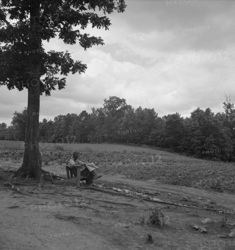 Negro tenant farmer reading paper on a hot Saturday afternoon, Chatham County, North Carolina, 1939. Creator: Dorothea Lange.