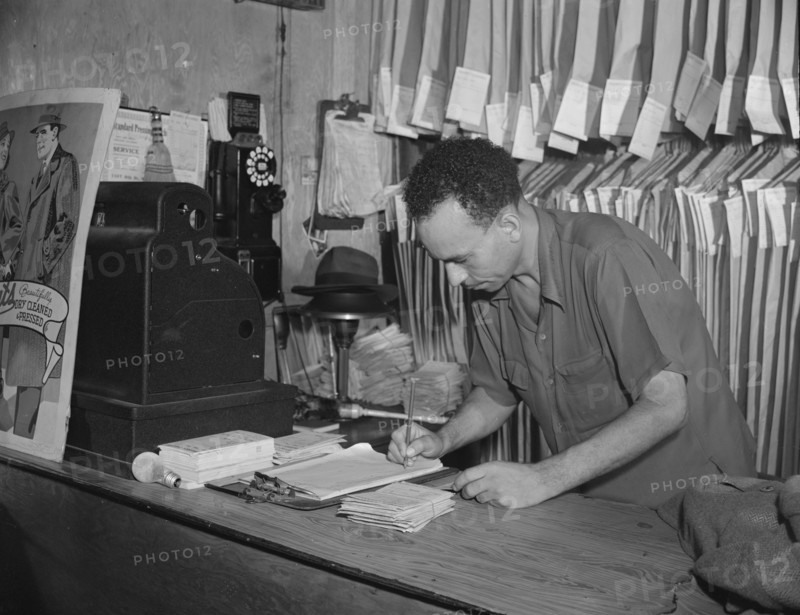 A tailor in Frank's cleaning and pressing establishment checking..., Washington, D.C., 1942. Creator: Gordon Parks.