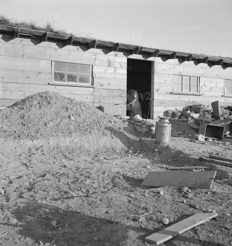 Mrs. Dougherty in doorway of basement house. Warm Springs, Malheur County, Oregon.