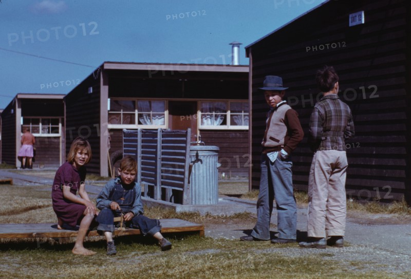 Boy building a model airplane while other children look on, FSA labor camp, Robstown, Tex., 1942. Creator: Arthur Rothstein.