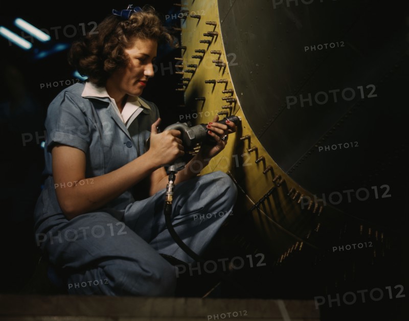 Riveter at work on Consolidated bomber, Consolidated Aircraft Corp., Fort Worth, Texas, 1942. Creator: Howard Hollem.