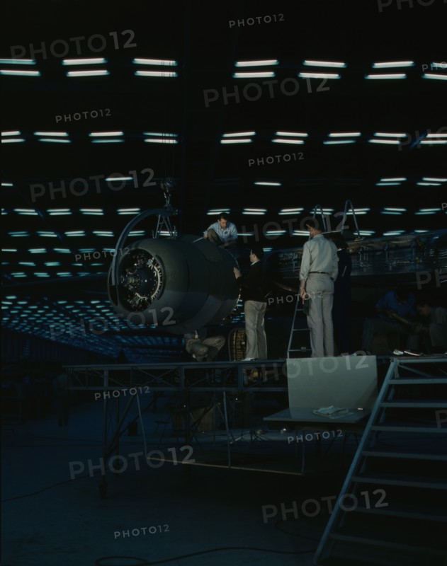 Lowering an engine in place in assembling...Consolidated Aircraft Corp..., Fort Worth, Texas, 1942. Creator: Howard Hollem.