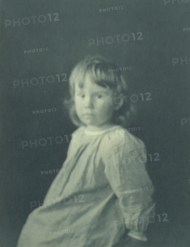 Seated girl with body facing left looking at the camera, c1900.