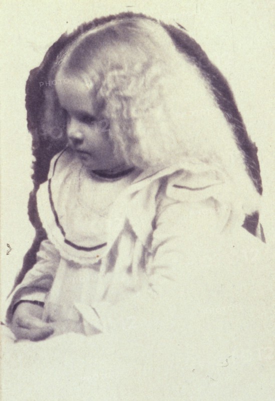 Young fair haired girl seated with hands in her lap, c1900.