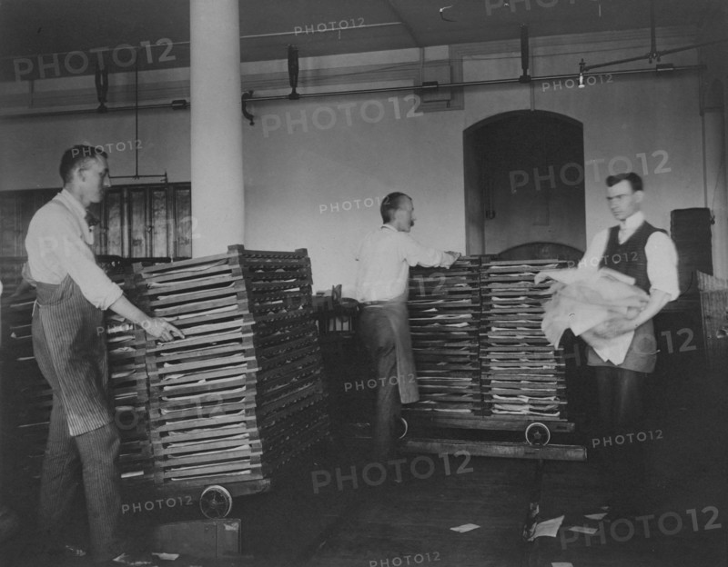 Workers moving newly printed currency into a drying box where sheets will dry before...c1890. Creator: Frances Benjamin Johnston.