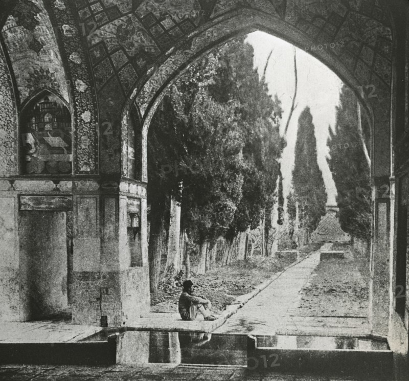 Reproduction of print showing Garden at Fin-Nahe¯, Kashan, Iran. Man seated under arch , c1920. Creator: Frances Benjamin Johnston.