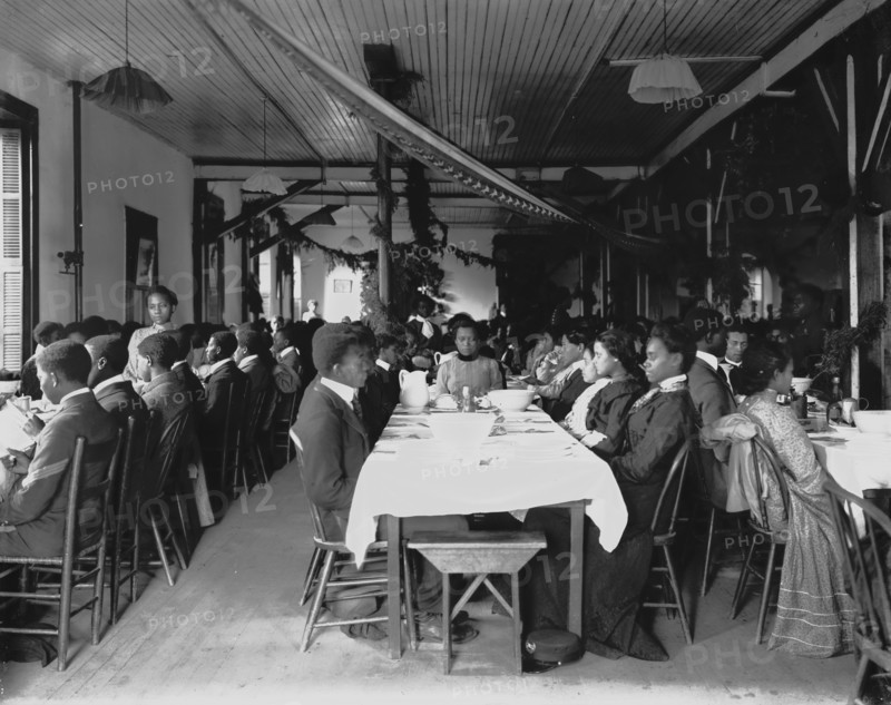 Interior view of dining hall, decorated for the holidays, with students... Tuskegee Institute, c1902 Creator: Frances Benjamin Johnston.