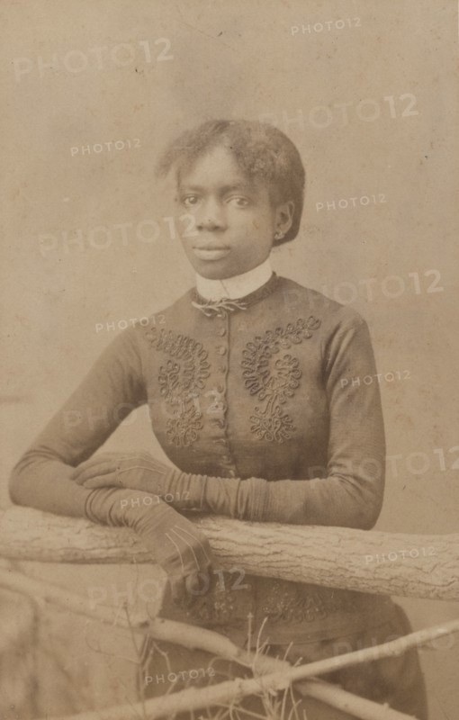 Unidentified young woman wearing gloves, leaning on prop fence, c1880. Creator: H. A. Insley.