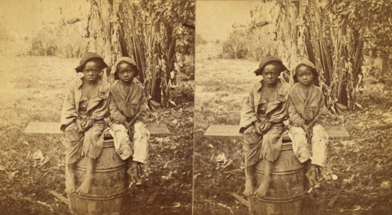 Happy little nig's, [Two boys sitting on a barrel in a field], (1868-1900?). Creator: Unknown.