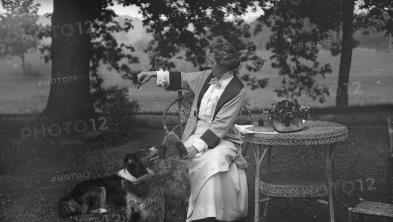Tarbell, Ida, Miss, with dogs, seated outdoors, 1912 or 1913. Creator: Arnold Genthe.