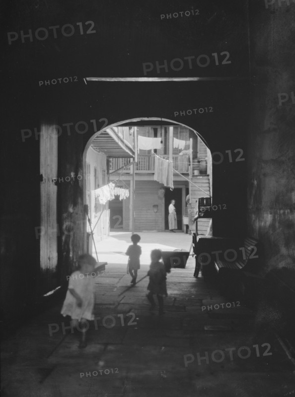 Children playing in an arched passageway, New Orleans, between 1920 and 1926. Creator: Arnold Genthe.