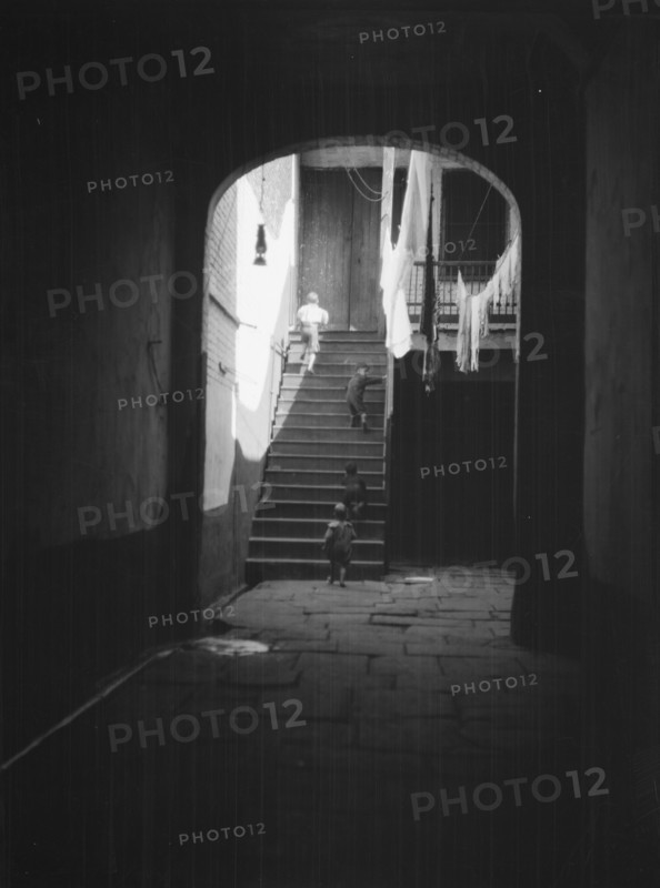 View of a courtyard through an arched passageway, New Orleans, between 1920 and 1926. Creator: Arnold Genthe.