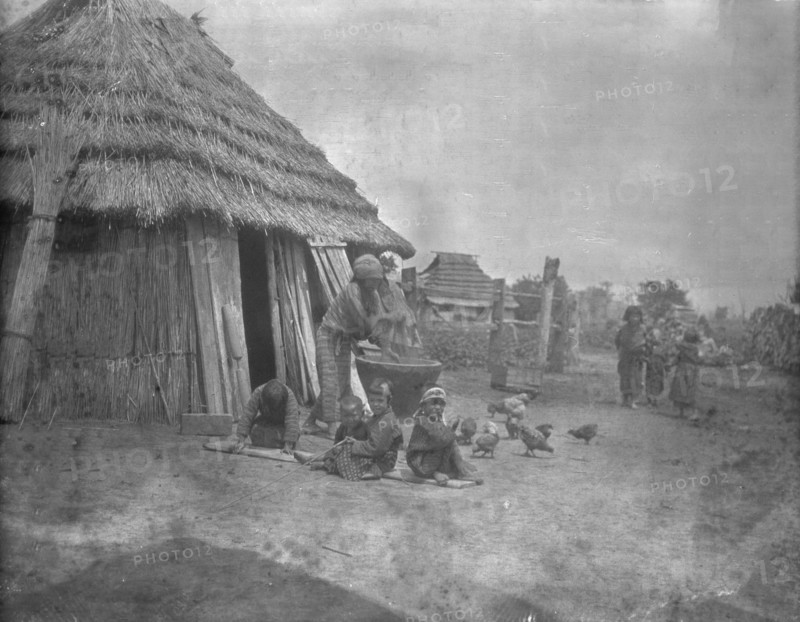 Ainu women and children outside a hut, 1908. Creator: Arnold Genthe.