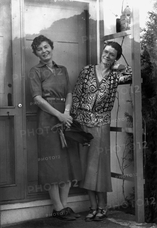 Mrs. Mary Benson and Alice DeLamar, standing by the door of a house, 1933. Creator: Arnold Genthe.