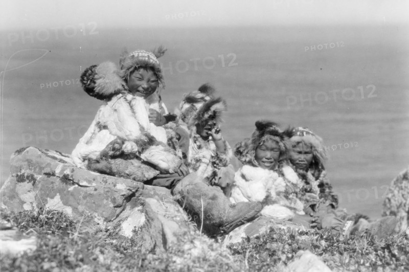 Four Eskimo children, at edge of cliff, in holiday costume, Nunivak, Alaska, c1929. Creator: Edward Sheriff Curtis.