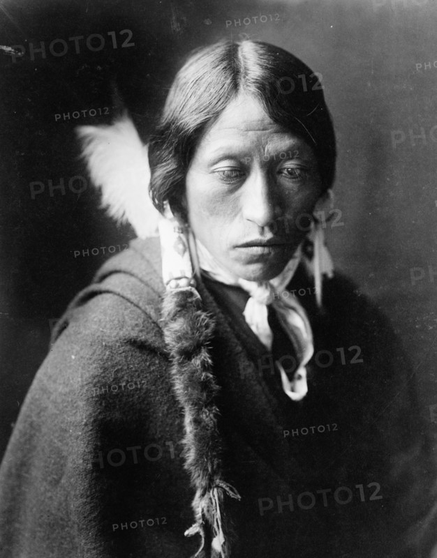 Jicarilla man, head-and-shoulders portrait, facing slightly right, with fur wrapped braids..., c1905 Creator: Edward Sheriff Curtis.