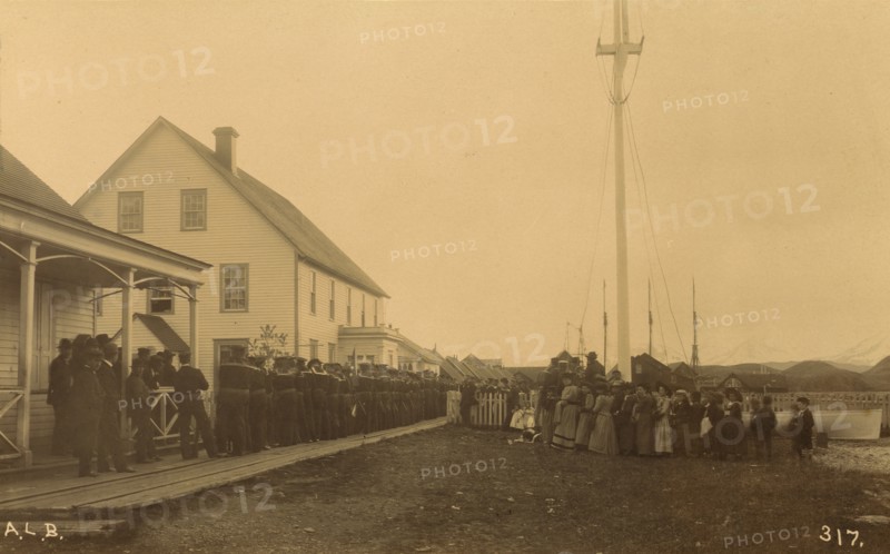 Sailors standing in line on boardwalk with a group of local women and men standing..., 1894 or 1895. Creator: Alfred Lee Broadbent.