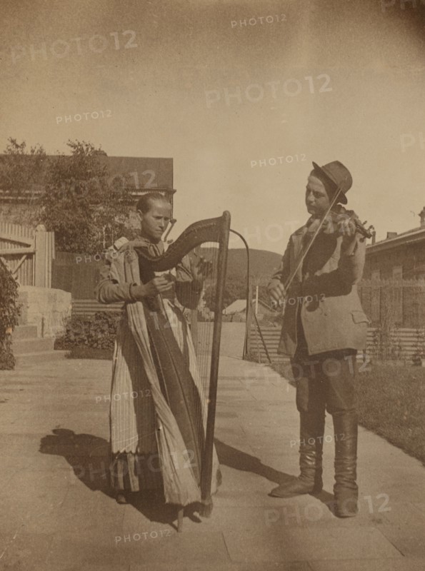 Street musicians with a harp and violin in the upper yard of Dom Smith, Vladivostok, Russia, (1899?) Creator: Eleanor Lord Pray.
