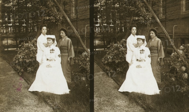 A western Red Cross female doctor(?) and two Japanese women posed in a garden, c1905. Creator: Underwood & Underwood.