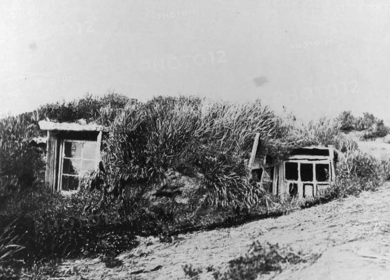 An Aleut house, which is a hole in the earth covered with a framework of driftwood..., c1900-c1930. Creator: Unknown.