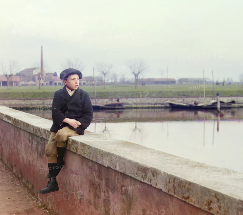Boy sitting on sea wall, between 1905 and 1915.  Creator: Sergey Mikhaylovich Prokudin-Gorsky.