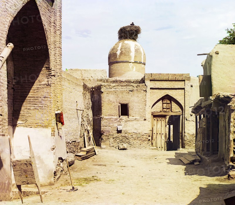 View of a courtyard, adobe buildings, and a bird's nest atop a dome, between 1905 and 1915. Creator: Sergey Mikhaylovich Prokudin-Gorsky.