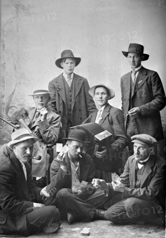 Group photo of men with musical instruments and playing cards, 1915.  Creator: Unknown.
