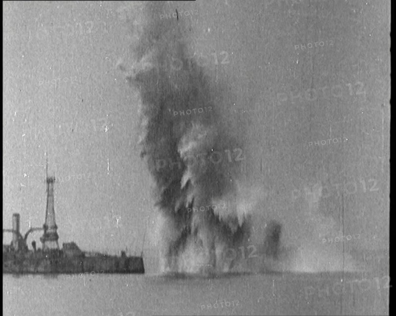 Bombs Dropped from Planes Exploding near a Warship, 1922. Creator: British Pathe Ltd.