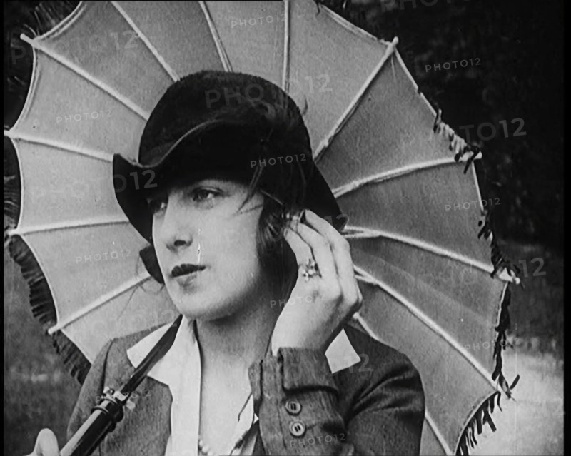 Fashionable Lady Sitting in a Garden Wearing Headphones and Carrying a Parasol, 1922. Creator: British Pathe Ltd.