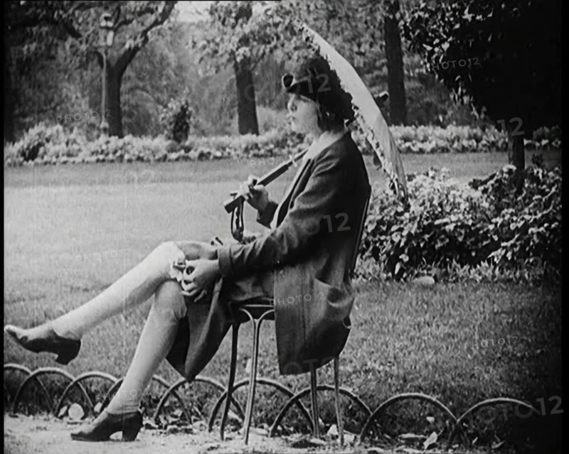 Fashionable Lady Sitting in a Garden Wearing Headphones and Carrying a Parasol, 1922. Creator: British Pathe Ltd.