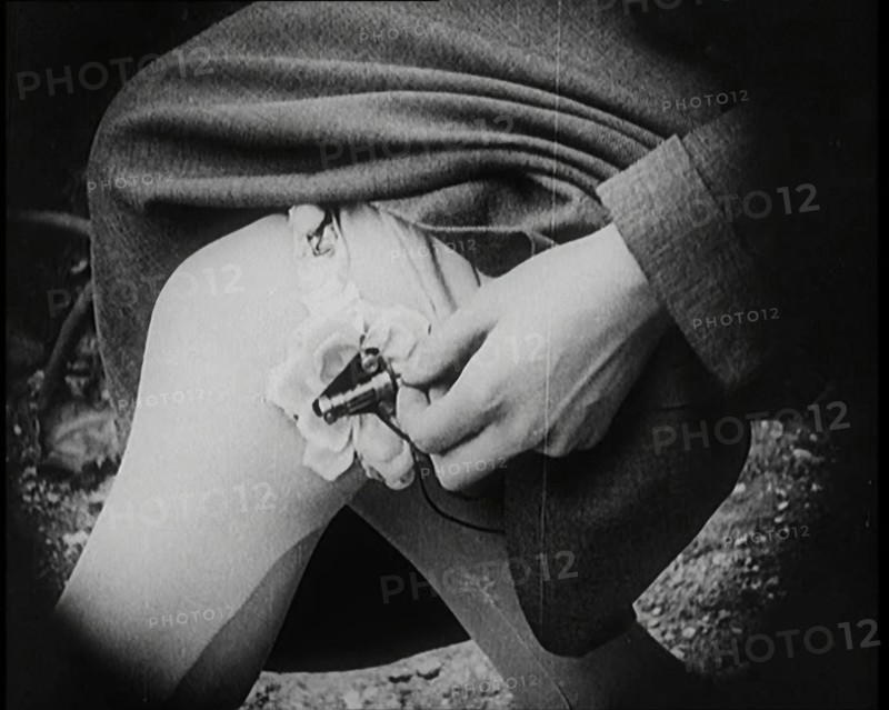 Fashionable Lady Sitting in a Garden, Adjusting Dials on a Miniature Wireless Radio in Her..., 1922. Creator: British Pathe Ltd.