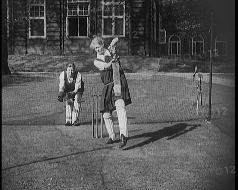 Two Female Civilians Wearing Gymslips and Batting Pads Preparing to Bat in a Playing Field, 1920. Creator: British Pathe Ltd.