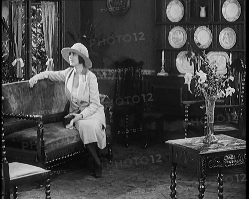 A Female Civilian Modelling a Two Piece Suit and Hat Sitting on a Sofa by a Window in a Draw... 1920 Creator: British Pathe Ltd.