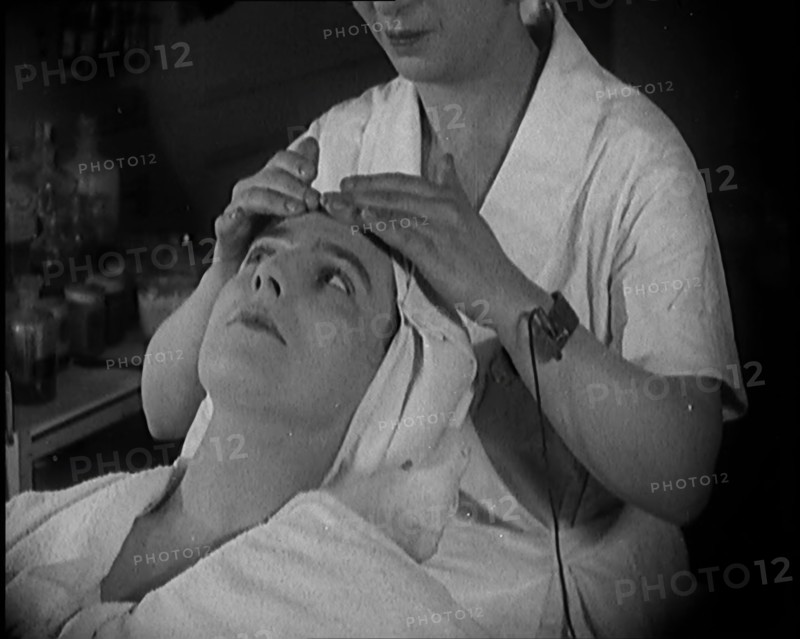 Female Civilian Having Her Face Massaged by Another Female Civilian Wearing an Electric, ... 1920. Creator: British Pathe Ltd.