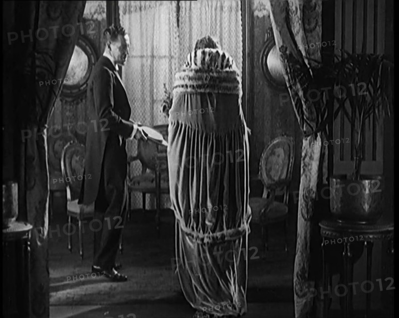 A Civilian Couple Wearing Evening Outfits Entering a Drawing Room, 1920. Creator: British Pathe Ltd.