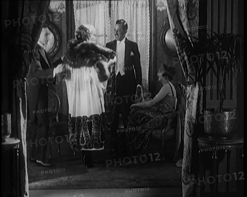 A Male Civilian Helping a Female Civilian Remove Her Fur Trimmed Coat Revealing an Ornated Gown, 192 Creator: British Pathe Ltd.