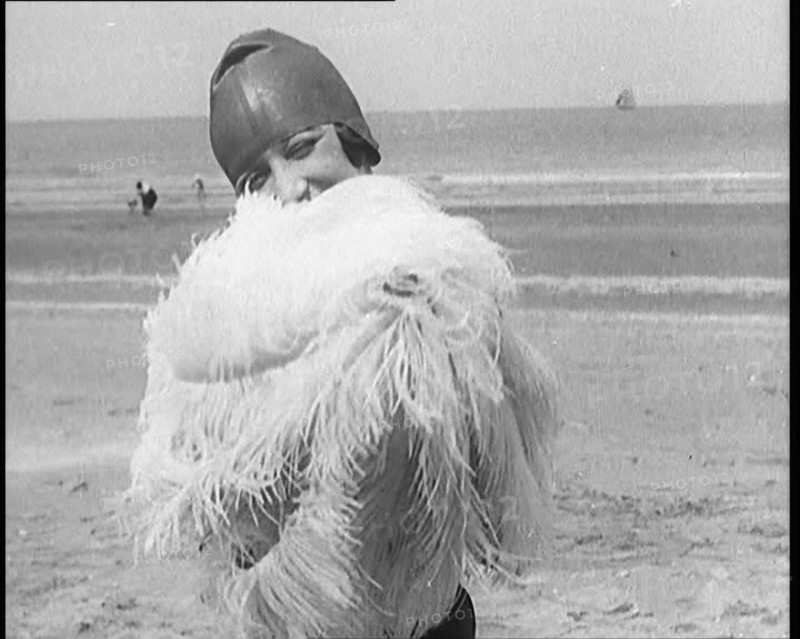 Female Civilian Wearing a Swimsuit Holding a Feathered Parasol at the Beach, 1920. Creator: British Pathe Ltd.