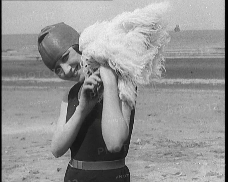 Female Civilian Wearing a Swimsuit Holding a Feathered Parasol at the Beach, 1920. Creator: British Pathe Ltd.