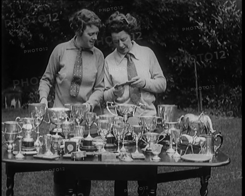 Two Female Civilians Standing Behind a Table Loaded with Trophies, 1920. Creator: British Pathe Ltd.
